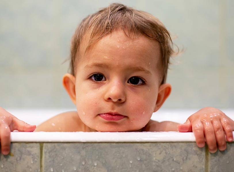 Baby leaning head out of the tub