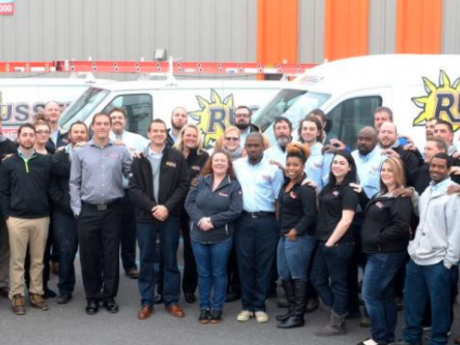 Russell's team posing outside building and fleet of Russell's vans