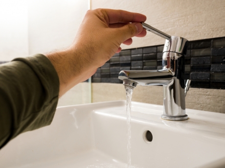 Man turning on bathroom tap with low water pressure