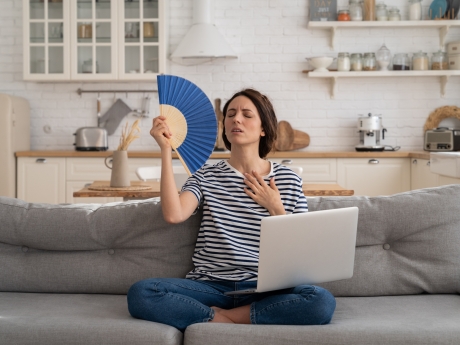 woman hot using a paper fan to cool off