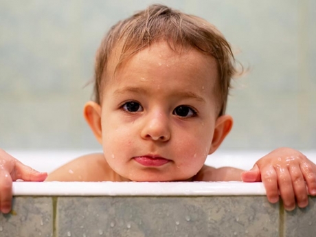 Baby leaning head out of the tub